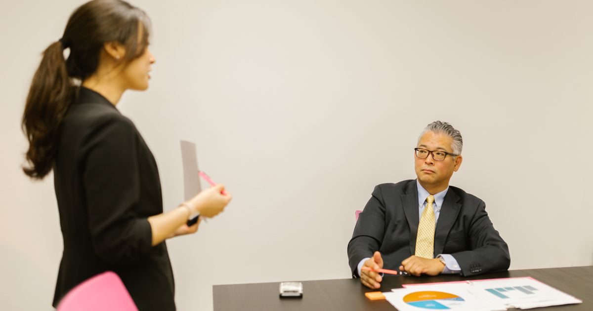 A professional woman presenting to a colleague during a business meeting in an office setting.